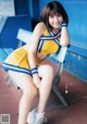 A woman in a cheerleading uniform sitting on a bench.