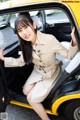 A woman sitting in the driver's seat of a yellow taxi.