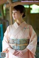 A woman in a pink kimono is posing for a picture.