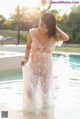 A woman in a white lace dress standing in a pool.