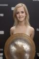 A woman holding a large metal shield in her hands.