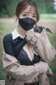 A woman wearing a black face mask in a park.