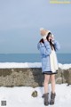 A woman standing on a wall in the snow.