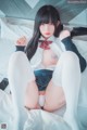 A woman in a school uniform is sitting on a bed.