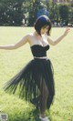 A woman in a black dress is dancing in the grass.