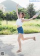 A woman in a white top and blue shorts is jumping in the air.