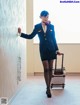 A woman in a blue uniform with a suitcase.