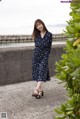 A woman in a blue dress standing on a sidewalk.