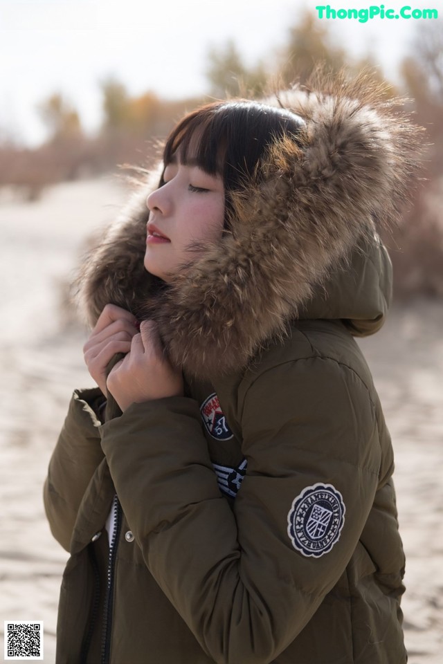 A woman in a parka with a fur hood on her head.